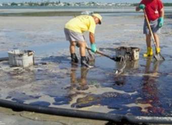 Hombres limpiando derrame de petróleo en la playa